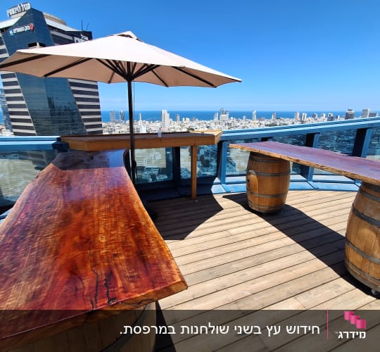 מרפסת עם שולחנות עץ ונוף לעיר
